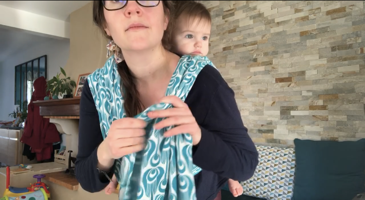 photo d'une installation d'un bébé en portage dos avec une écharpe tissée