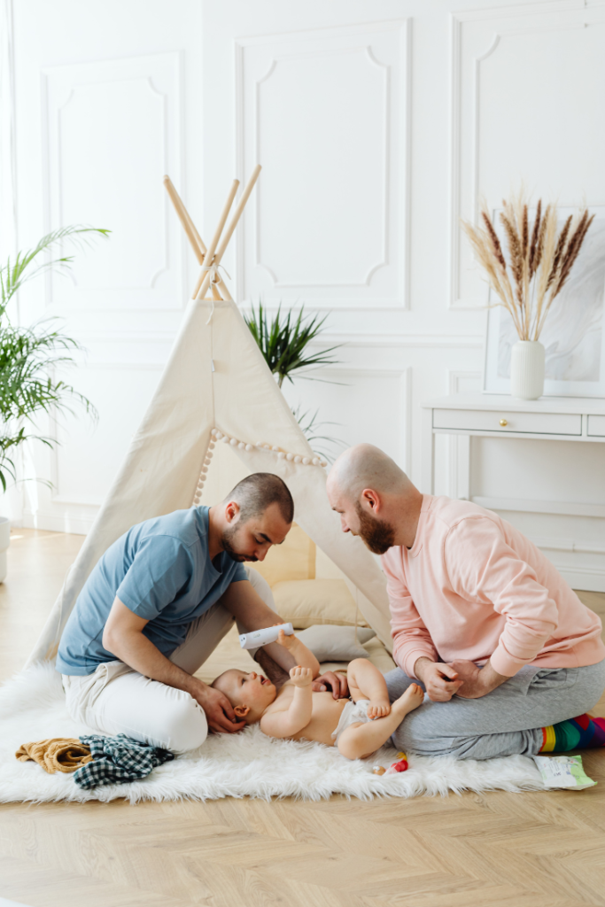 photo d'un couple d'homme qui jouent avec leurs papas, installés sur un tapis, devant un tipis - consultations parentalité - allaitement sommeil portage doula angers maine et loire 49